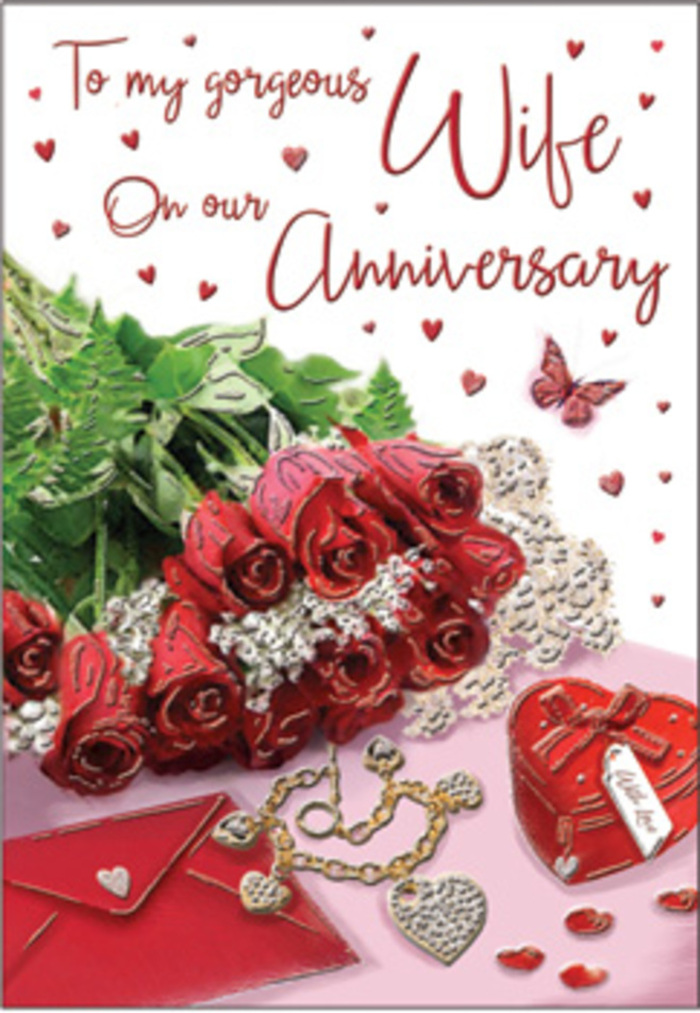 A rich, heartfelt anniversary tableau is arranged as though on a polished table in a characterful Fitzrovia flat, capturing the warmth of a long-loved relationship. The centrepiece is a bouquet of classic red roses, each bloom generously open, their petals forming soft, velvety cups that seem to cradle the light. The flowers are elegantly wrapped and threaded with lush green foliage, creating a sense of fullness and abundance, like the leafy pockets around Rathbone Square. Around the bouquet, small but meaningful accents tell a story of treasured years: an elegant jewellery set placed with care, its stones and metal gleaming gently; a vivid red gift box that hints at surprises shared; and a neatly positioned envelope ready to reveal heartfelt anniversary words. Fine lace details and delicate heart motifs are woven through the design, their intricate patterns catching the eye and adding a layer of gentle nostalgia. The palette of deep reds, warm whites, and touches of gold and blush evokes a luxurious yet intimate mood, much like a quiet dinner for two tucked away in one of Fitzrovia's side streets. Various textures-velvet-like petals, crisp card, smooth ribbon, and polished metal-interplay under the soft ambient lighting, giving the entire scene depth and dimension. The partially visible scripted message on the card adds a lyrical element, suggesting promises, gratitude, and shared memories. Crafted with the sensitivity of an experienced florist, this image celebrates the kind of love that feels like a comforting embrace, perfectly at home in the vibrant heart of London's West End.