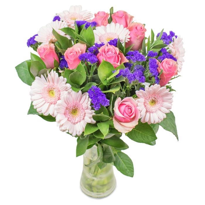 This stunning arrangement from Fitzrovia Flowers stands as a sophisticated ensemble in a transparent vase, its fresh blooms illuminated by natural, city-centre light. Central to the design are seven to nine pink roses, layered from pastel to deeper rose, many with petals tightly curled or just starting to flourish, capturing their romantic, spiral charm. Around them, five or more gerbera daisies in gentle blush unfold with large, radiant heads and nearly white centres. Pops of vivid purple statice, with their textured clusters, intersperse among the main blooms, providing a bold, creative accent that hints at the vibrant art scene of Fitzrovia. Deep green foliage emerges beneath, lush and abundant, evoking the leafy calm of Fitzrovia's garden squares. The slender vase showcases stems and fresh water, a nod to local delivery and the commitment to freshness Fitzrovia Flowers is known for. Ideal for birthdays, anniversaries, or brightening a workplace near Goodge Street, this bouquet conveys celebration, connection, and the enduring beauty found in Fitzrovia's heart.